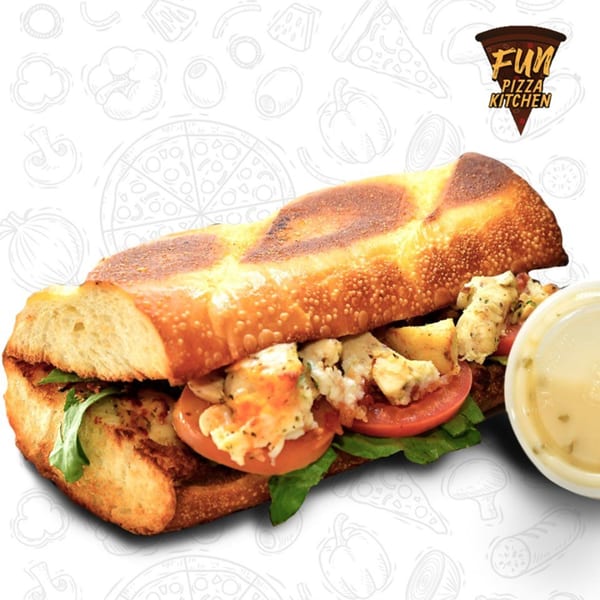 A Fun Pizza Kitchen sub sandwich with chicken, tomatoes, and lettuce, served with a side of dressing.