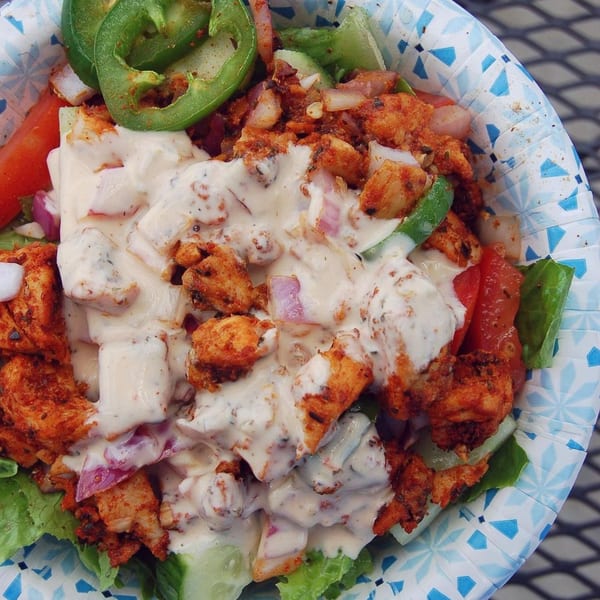 Spicy chicken salad with jalapeños, red onions, and creamy dressing in a paper bowl.