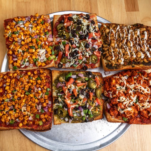 Six rectangular Fun Pizza Kitchen pizzas with various toppings on a metal tray.